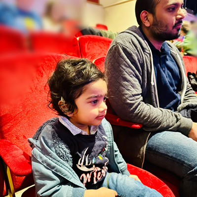 Boy sat in seat at theatre, his dad is to his right