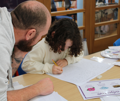 a father and son drawing and writing a story on a paper storyboard.