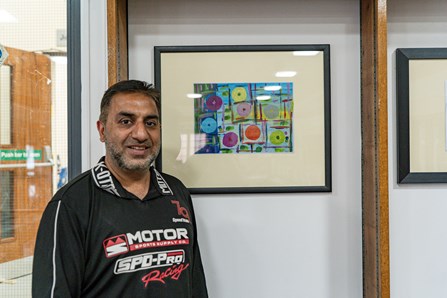 Learner, Ashraf, stood to the left of his artwork on display in our gallery.