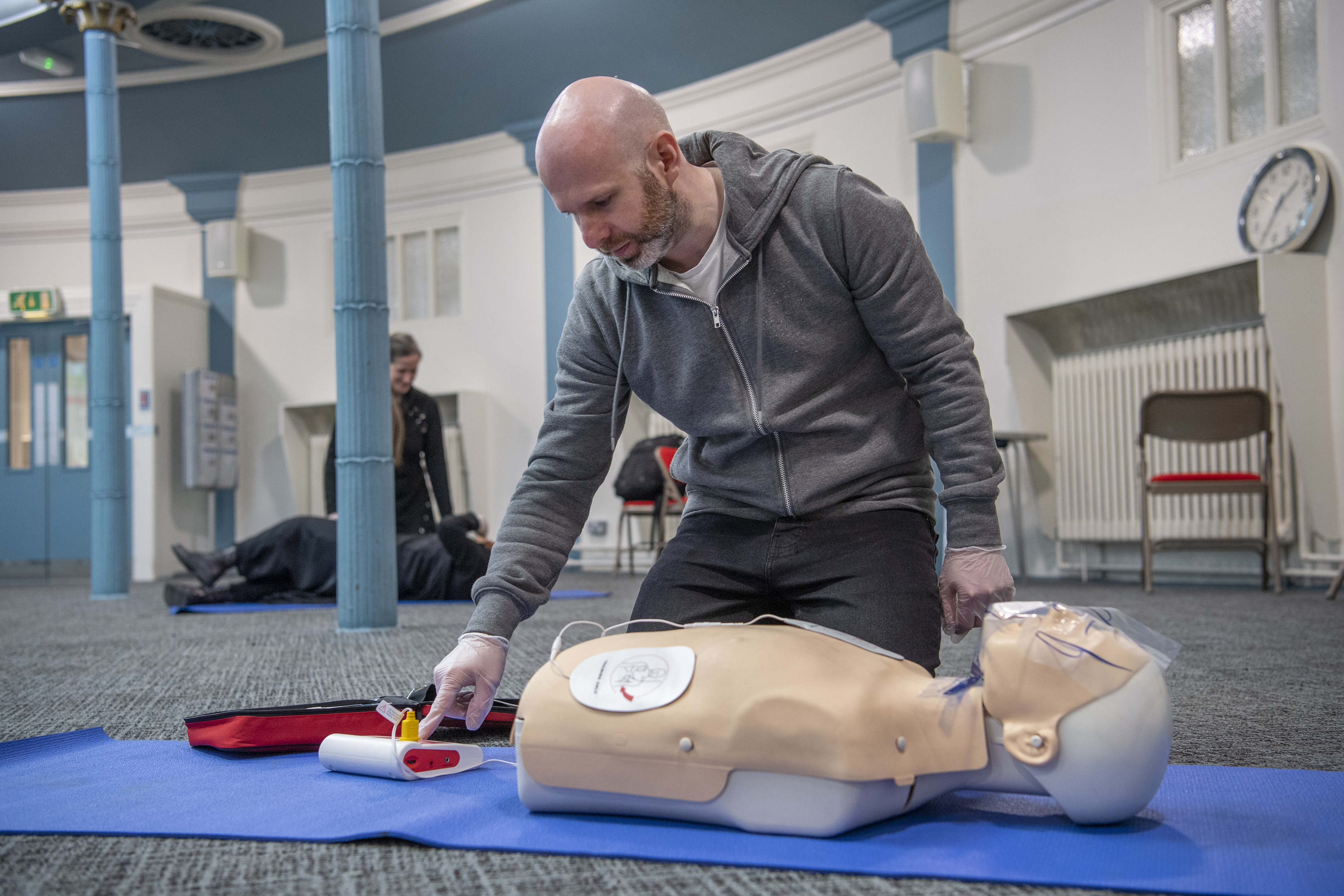 Male learner during CPR course, with a dummy on the mat.